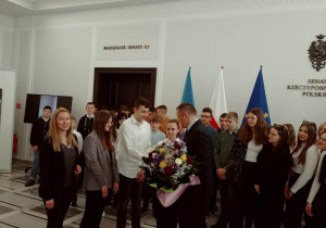 Uczniowie klas VIII wraz z panią wójt Iwoną Łuszcz- Krawczyk wręczają kwiaty panu R.Amrozikowi.