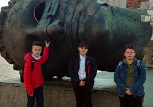zdjęcie chłopców przed rzeźbą na rynku głównym w Krakowie