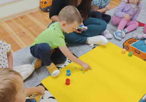 Dzieci w grupie Biedronki stawiają kropki maczając palec w farbie.
