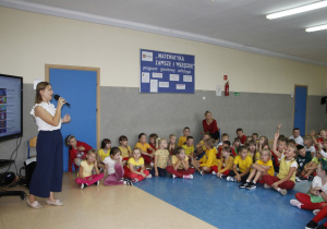 na zdjęciu widać grupę dzieci oraz nauczyciela języka angielskiego z mikrofonem.