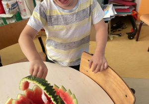 Chłopiec z koszyka arbuzowego nabiera łyżeczką kawałek arbuza
