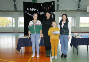 zdjęcie ukazuje trzy dorosłe kobiety i dziewczynkę odbierającą nagrodę