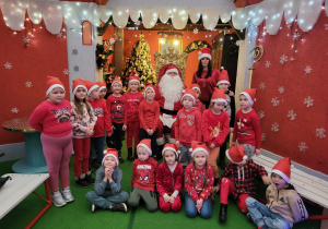 Pamiątkowe zdjęcie 6 latków z wychowawcą, Świętym Mikołajem w Krainie Świętego Mikołaja. Wspólne śpiewnie piosenki dla Mikołaja.