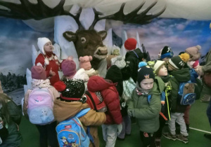 Zdjęcie grupowe przedszkolaków na tle poroża jelenia.
