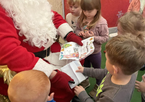 Dzieci przedszkolne wręczają listy Mikołajowi.