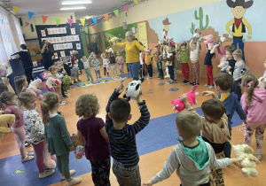 Dzieci z trzech grup przedszkolnych tańczą w kole.