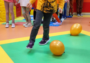 Dzieci wykonują slalom miedzy balonami.