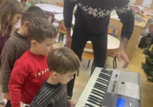 Dzieci ustawione w kolejce grają na keyboardzie