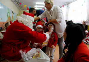 Mikołaj wręcza dzieciom z grupy MISIE prezenty a pan wójt częstuje cukierkami