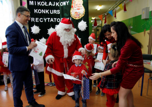 Wręczanie przez Mikołaja i pana wójta dyplomów i nagród podczas Mikołajkowego Konkursu Recytatorskiego.