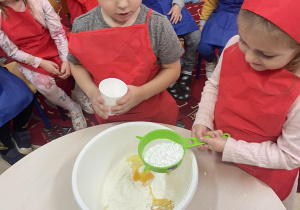 Chłopiec i dziewczyna wsypują cukier puder do miski.