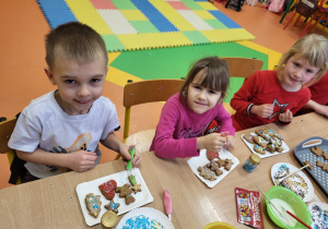 Dzieci ze skupieniem uwagi dekorują lukrem pierniczki.
