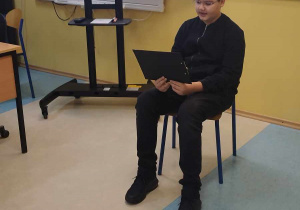 1.Zdjęcie przedstawia chłopca siedzącego w klasie, który czyta.