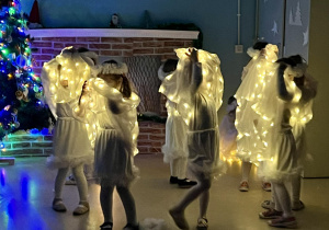 Piruety dziewczynek w pelerynach ze światełkami.