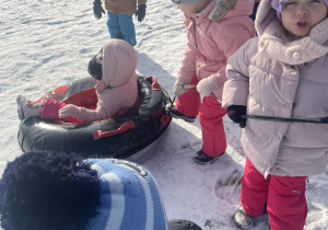 Dzieci ciągną ponton po śniegu.