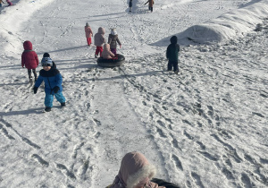 Dzieci na tle górki śniegowej.