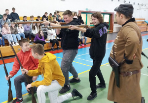 Czterech uczniów z klasy 8 prezentują uczniom broń z okresu powstania