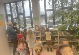 Dzieci żegnają się z panią z biblioteki, a pani pokazuje dzieciom przez okno szkołę, która znajduje się bardzo blisko.