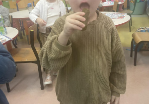 Chłopiec zjada kiszonego ogórka.