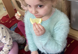 Dziewczynka smakuje cytrynę.