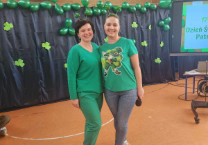 na zdjęciu widzimy dwie uśmiechnięte kobiety w zielonych strojach, w tle zielona dekoracja z balonów