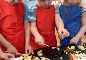Dzieci wrzucają pokrojone warzywa do miski