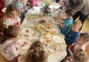 Dzieci wraz z Panią od Religii rozmawiają podczas śniadania Wielkanocnego.