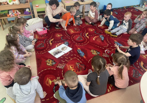 Mama Jana przekazuje dzieciom siedzącym na dywanie informacje o jeżu.
