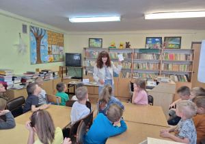 Dzieci z uwagą słuchają pani bibliotekarki na temat swojej pracy.