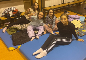 Zosia, Marta, Ala i Maja w sali gimnastycznej szykują śpiwory i materace na nocowanie w szkole