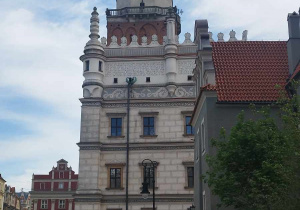 Na zdjęciu widnieje zabytkowy ratusz na starym mieście w Poznaniu oraz grupa uczestników wycieczki.