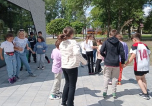 uczniowie na parkingu w Płowcach z p. Agatą tańczą Belgijkę