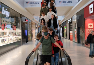 Grupa uczniów opuszczających kino na ruchomych schodach