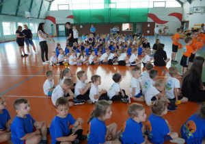 Dzieci siedzą w grupach podczas otwarcia Olimpiady