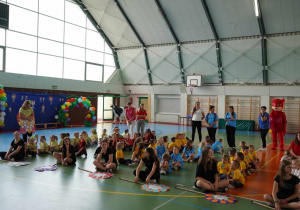 Dzieci siedzą w grupach podczas otwarcia Olimpiady
