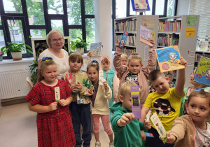 Dzieci trzymają wypożyczone książki z biblioteki .