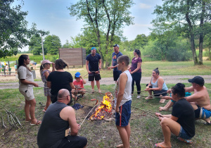 Dzieci i rodzice pieką kiełbaski.