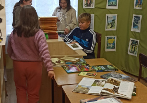 Uczniowie SP w Rzeczycy czytają książki o zwierzętach w bibliotece szkolnej.