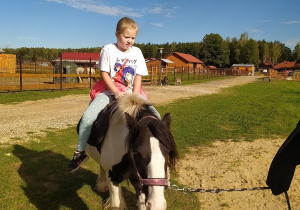 Dziewczynka jeździ na koniku.