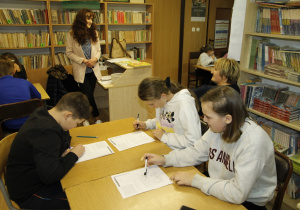 Uczniowie biorą udział w konkursie z wiedzy ogólnej w bibliotece szkolnej.