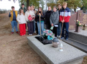 Dzieci stoją przy posprzątanym grobie nieznanego żołnierza na cmentarzu w Rzeczycy