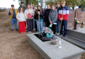 Dzieci stoją przy posprzątanym grobie nieznanego żołnierza na cmentarzu w Rzeczycy.