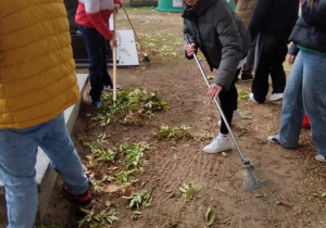 Dzieci sprzątają grób nieznanego żołnierza na cmentarzu w Rzeczycy.