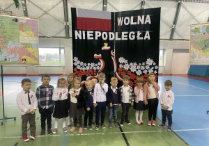 Grupa Motylki w strojach galowych na tle ścianki Wolna Niepodległa