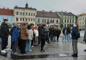 Uczniowie na rynku na tle kamienic i dawnego hotelu Herz stoją na miejscu zarysu fundamentów schronu przeciwlotniczego z II wojny światowej.