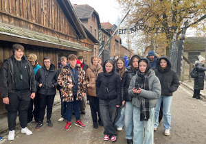 Grupa uczniów pod bramą z napisem „Arbeit macht frei”.