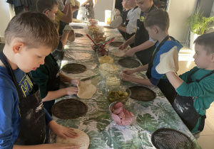 Uczniowie z klasy II przygotowują formy do ciasta pizzy.