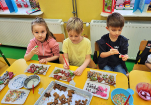 Dzieci ze skupieniem uwagi dekorują lukrem pierniczki