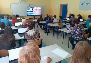 Uczestnicy zajęć oglądają film o bezpiecznym korzystaniu z poczty elektronicznej, wyświetlany na ekranie interaktywnym.