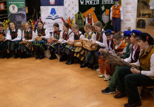 "Wieś polska w poezji i prozie" - grupa uczniów śpiewa, siedząc w pół kole.